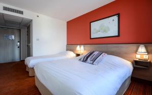 2 letti in una camera d'albergo con pareti rosse di Ace Hotel Annecy ad Annecy