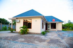 una pequeña casa blanca con techo azul en Joleen Safari Park, en Dar es Salaam