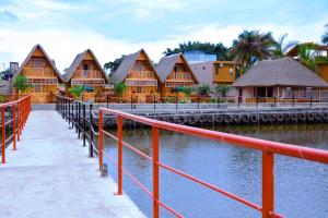 uma fileira de edifícios de madeira com água e um corrimão vermelho em Pelican Lodge & Marina em Entebbe