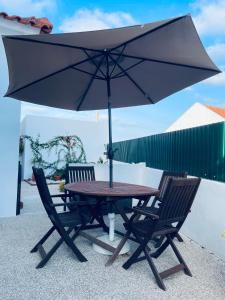 een tafel en twee stoelen met een paraplu bij Casa do Canto - Uma casa no campo, perto da praia. in Óbidos