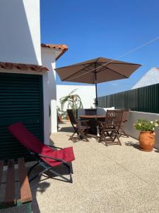 een patio met een tafel en stoelen en een parasol bij Casa do Canto - Uma casa no campo, perto da praia. in Óbidos