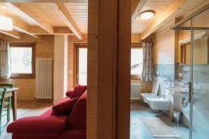 een woonkamer met een rode bank en een badkamer bij Chalet Gaspard in Valtournenche