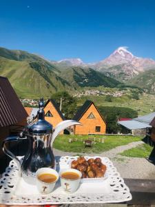 une table avec deux tasses de thé et une assiette de nourriture dans l'établissement Guesthouse Elli & Cottages, à Kazbegi