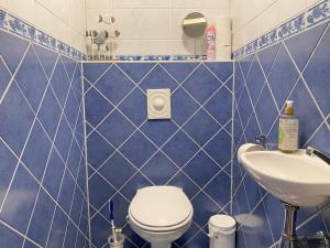 La salle de bains est pourvue de carrelage bleu, de toilettes et d'un lavabo. dans l'établissement Callantsoger Staete A306, à Callantsoog