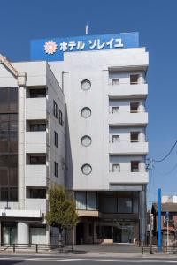 um edifício branco com uma placa em cima em Hotel Soleil em Iwaki