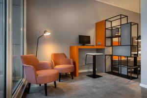 une salle d'attente avec des chaises orange et une télévision dans l'établissement Select Hotel Wiesbaden City, à Wiesbaden