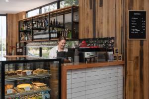 une femme se tient derrière le comptoir d'une boulangerie dans l'établissement Rydges South Park Adelaide, à Adélaïde