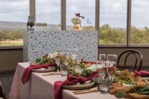 une table avec un chiffon de table blanc et des serviettes rouges dans l'établissement Rydges South Park Adelaide, à Adélaïde