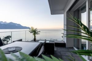 een tafel en stoelen op een balkon met uitzicht op het water bij Sunset Home, Appartement de luxe front de lac in Veytaux