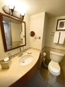 a bathroom with a sink and a toilet and a mirror at Costa Bahia Hotel Paseo Caribe in San Juan