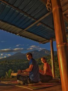 a man and a child sitting on the floor under a roof at Rinjani Houseboon in Senaru