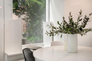 Una mesa blanca con un jarrón de flores. en Apartment Eewal 68, en Leeuwarden