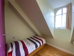 Cette petite chambre comprend un lit et une fenêtre. dans l'établissement Manoir Le Castel & Villa Beaumaris, à Saint-Malo