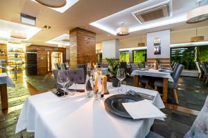 un restaurant avec des tables blanches, des chaises et des fenêtres dans l'établissement Hotel Żywiecki Medical SPA & Sport Żywiec, à Żywiec