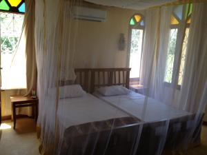 - une chambre avec un lit doté de draps blancs et de fenêtres dans l'établissement Marula Park, à Diani Beach