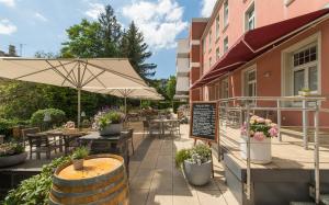 un patio con tavoli, sedie e ombrellone di Hotel Oranien Wiesbaden a Wiesbaden