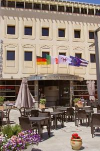 een restaurant met tafels en parasols voor een gebouw bij HR Hotel in Monfalcone