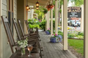 eine Veranda mit Stühlen, einem Glas Wein und Blumen in der Unterkunft Bar Harbor Grand Hotel in Bar Harbor