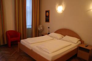 a bedroom with a bed and a red chair at Suite Hotel 200m zum Prater in Vienna