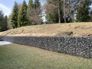 una pared de piedra frente a una colina con árboles en Cozy central apartment at a special price!, en Crans-Montana