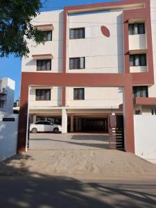 a white car parked in front of a building at Mayfair Service Apartments in Pīlamedu