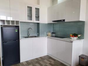 uma cozinha com armários brancos e um frigorífico preto em Minh Anh Hotel & Apartment em Hai Phong