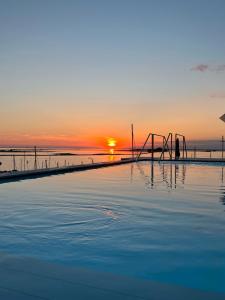 een zwembad met zonsondergang op de achtergrond bij Laguna Faro Suites - Adults Only & Free Beach in Grado