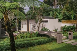 un jardín con un banco frente a una casa en Umah Shama, en Ubud