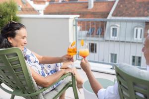 une femme assise sur une chaise tenant un verre de vin dans l'établissement Hotel Gollner, à Graz