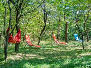 three chairs sitting in the grass in the woods at Casa de vacanta traditionala romaneasca in Schiuleşti