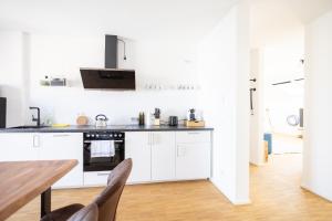 een keuken met witte kasten en een houten tafel bij Ko-Living - Captain's Suite - Altstadt - mit Küche, Smart TV & Balkon - 6P in Halle an der Saale