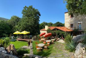 un jardin avec des tables et des parasols et un bâtiment dans l'établissement Azenha do Tio Luís, à Caminha