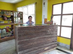 een vrouw die achter een houten toonbank in een kamer staat bij Hotel Mhelung in Darjeeling