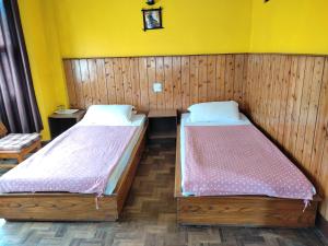 twee bedden in een kamer met gele muren bij Hotel Mhelung in Darjeeling