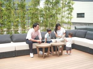 une famille assise sur un canapé avec deux tables dans l'établissement fav HIROSHIMA STADIUM, à Hiroshima