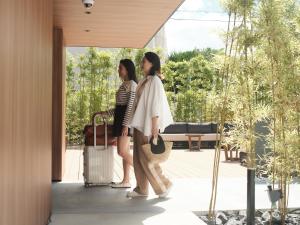 2 femmes debout sur une terrasse couverte avec leurs bagages dans l'établissement fav HIROSHIMA STADIUM, à Hiroshima