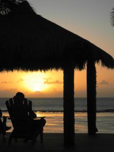 a person sitting in a chair under an umbrella on the beach at Sunset Resort in Rarotonga