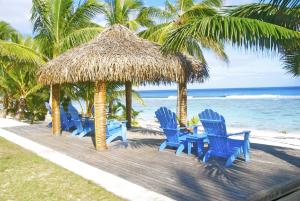 a group of blue chairs and a table on a beach at Sunset Resort in Rarotonga