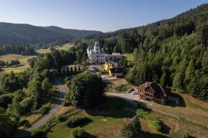 - une vue aérienne sur une grande maison blanche dans les montagnes dans l'établissement Hotel Villa Golf Cihelny, à Karlovy Vary