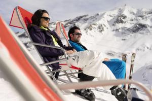 Un uomo e una donna seduti su una sedia nella neve di Belambra Clubs Arc 2000 - L'Aiguille Rouge - Ski pass included ad Arc 2000