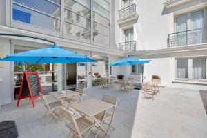 een patio met tafels, stoelen en parasols bij Best Western Hôtel Journel Antibes Juan-les-Pins in Antibes