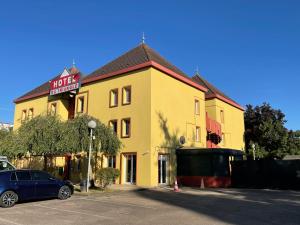 a yellow hotel with a car parked in front of it at Hotel du Triangle in Talange