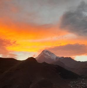 uma vista para uma montanha com um pôr-do-sol em Royal Galaxy apartment em Kazbegi