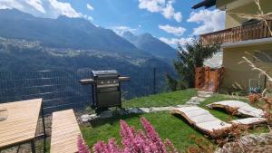 un patio trasero con una parrilla y montañas al fondo en Mattertal Lodge, en Embd