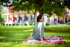 Eine Frau, die auf einer Picknickdecke auf dem Gras sitzt. in der Unterkunft Regina in Druskininkai