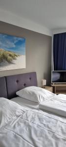 een slaapkamer met een wit bed en een flatscreen-tv bij Hotel & Gästehaus Rostock Lütten Klein in Rostock