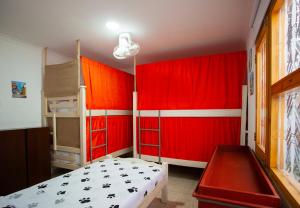 a bedroom with red walls and a bed and bunk beds at Hostal El Bando in Cartagena de Indias