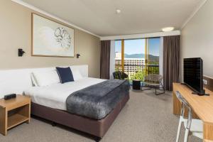 um quarto de hotel com uma cama, uma televisão e uma varanda em Pacific Hotel Cairns em Cairns