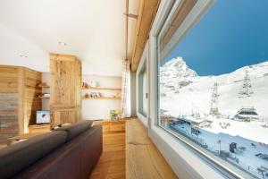 - un salon avec un canapé et une grande fenêtre dans l'établissement HelloChalet - Maison Rêve Blanc - Ski to door with Matterhorn view, à Breuil-Cervinia