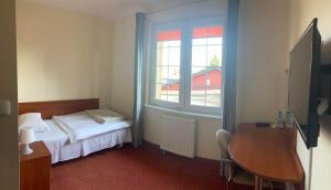 - une chambre avec un lit, un bureau et une fenêtre dans l'établissement Hotel Gryf, à Kościerzyna